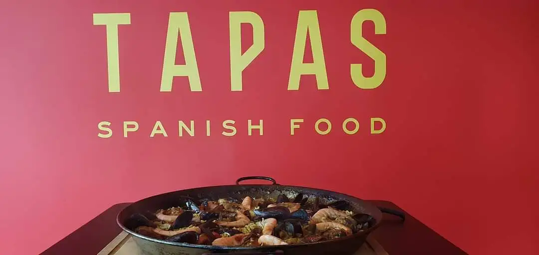 Grosse Paella-Pfanne vor der TAPAS-Logowand