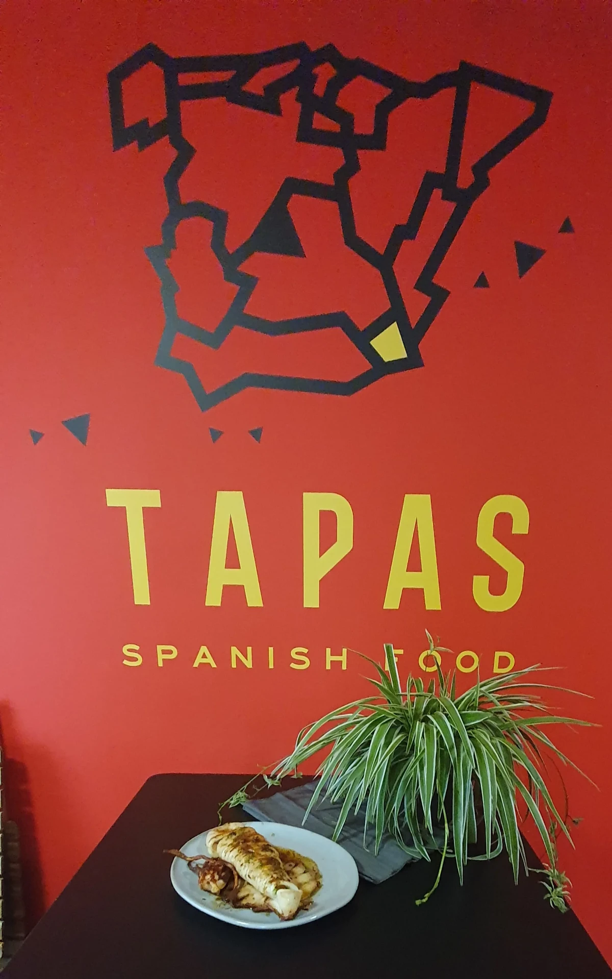 Tapas-Teller unter der Spanien-Karte an der roten Wand