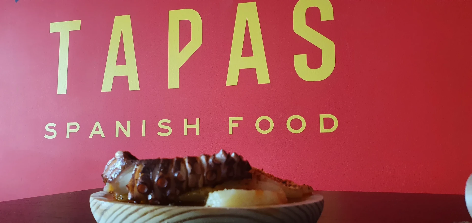 Pulpo-Tapa vor dem gelben TAPAS-Schriftzug
